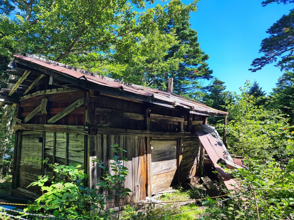 Abandoned mountain hut at the 2nd station of Mt. Fuji, surrounded by rocky slopes and alpine vegetation.